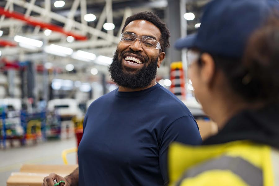 A person wearing safety glasses and smiling at another person