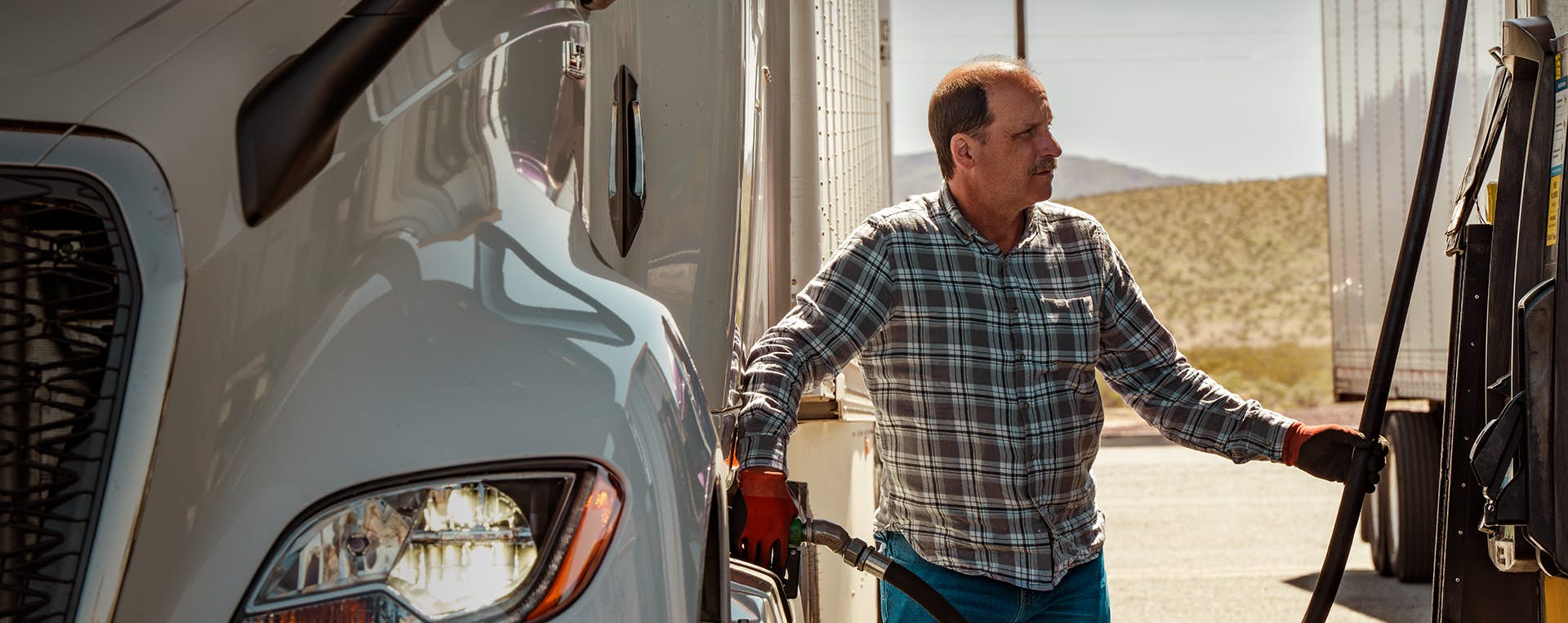 Truck driver filling a truck with fuel at a gas station